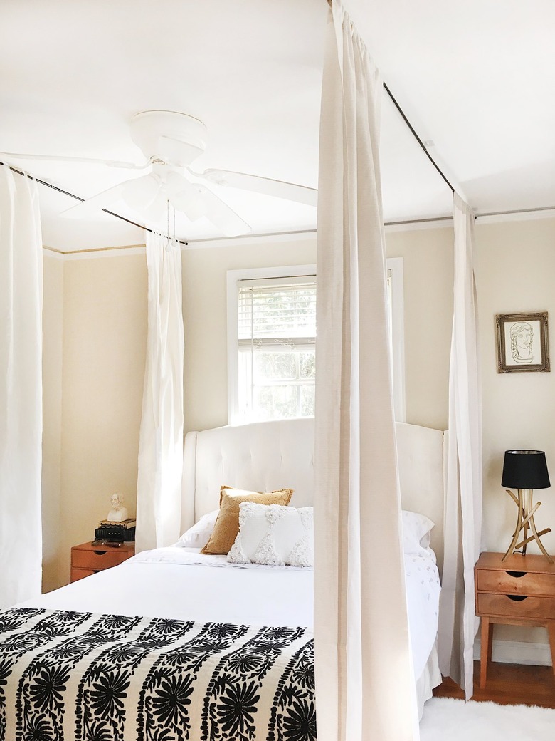 a bed with curtains hanging from the ceiling around it to create a canopy