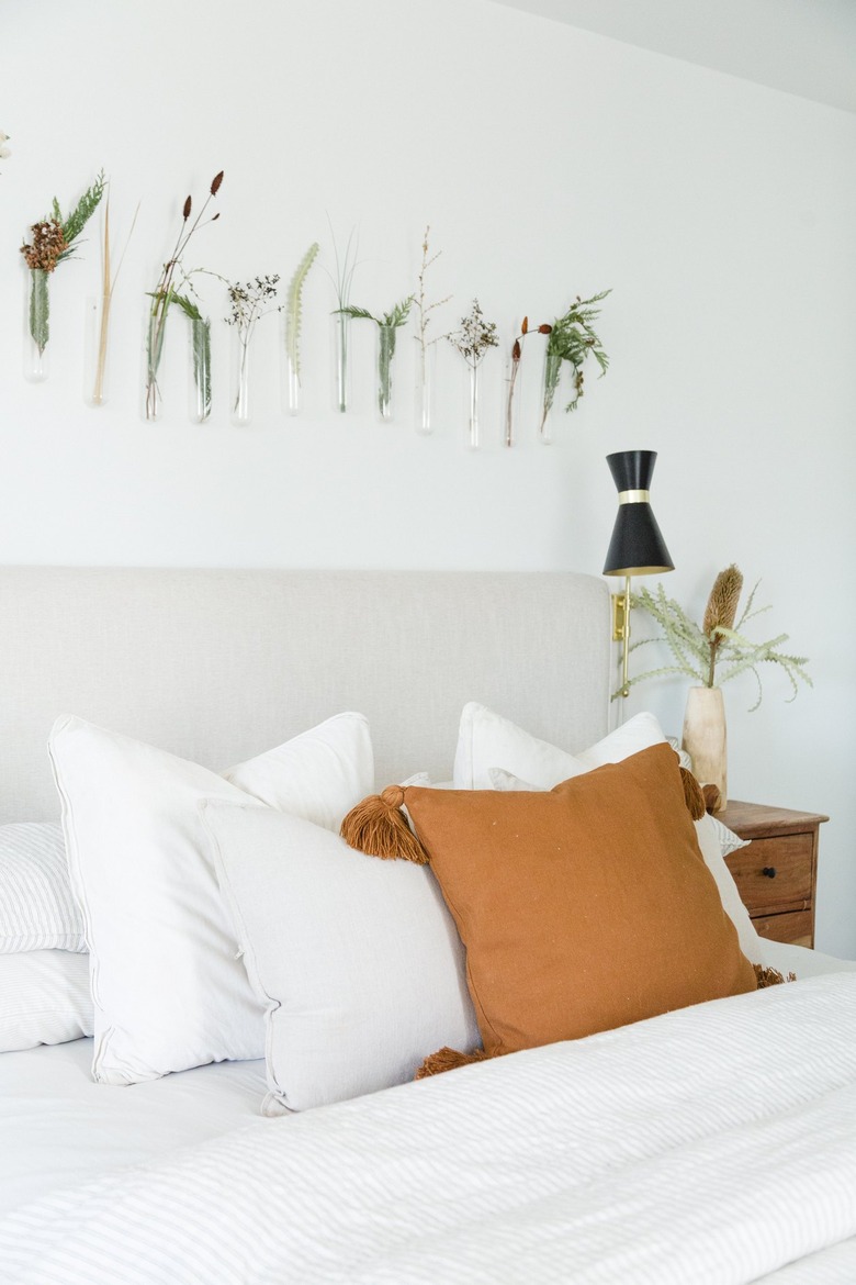 White boho bedroom with glass hanging vases above bed