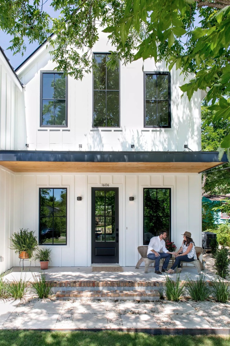 board and batten white siding on farmhouse with black windows and door
