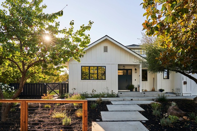 White farmhouse with stone path and black door and windows