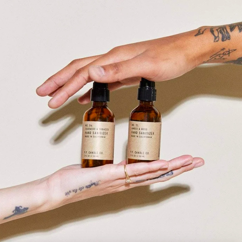 two hands holding two bottles of hand sanitizer