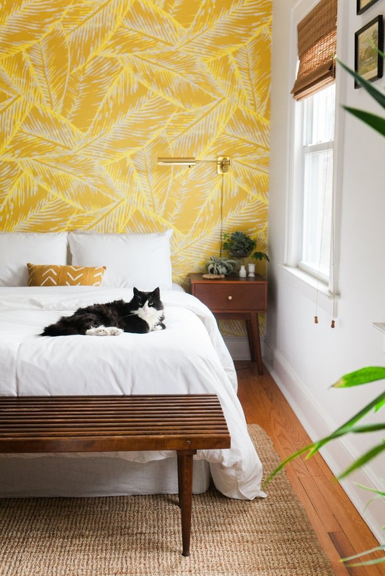 Yellow wallpaper in bedroom with cat on bed.