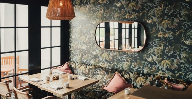 Dining room with dramatic print wallpaper and mirror on wall.
