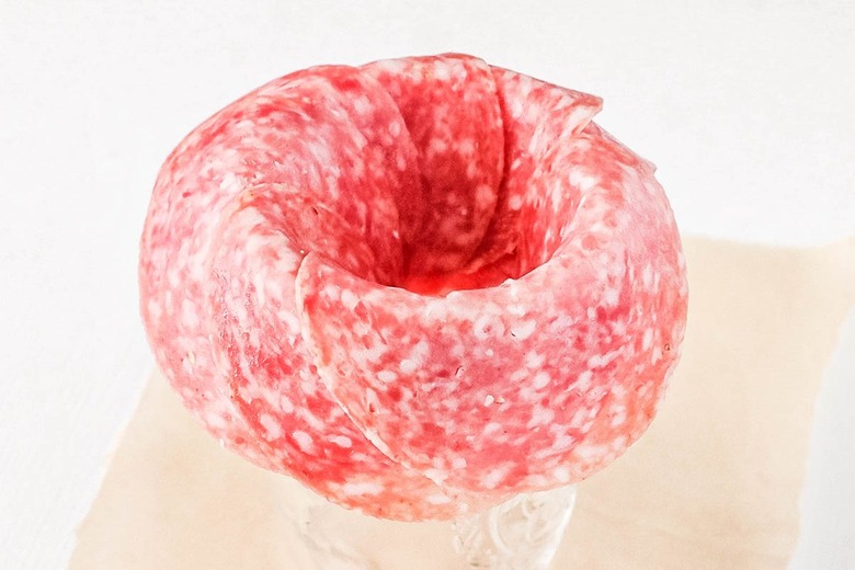 Continue folding salami over edge of jar
