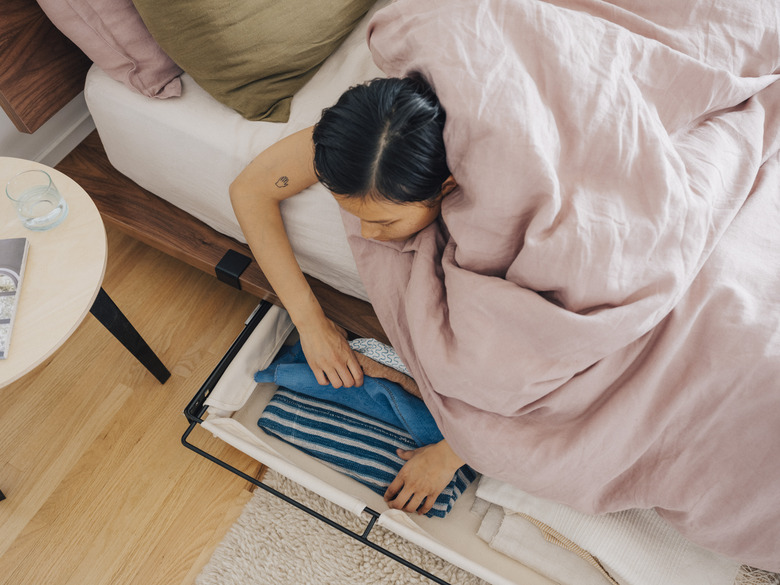 person in bed looking through underbed storage