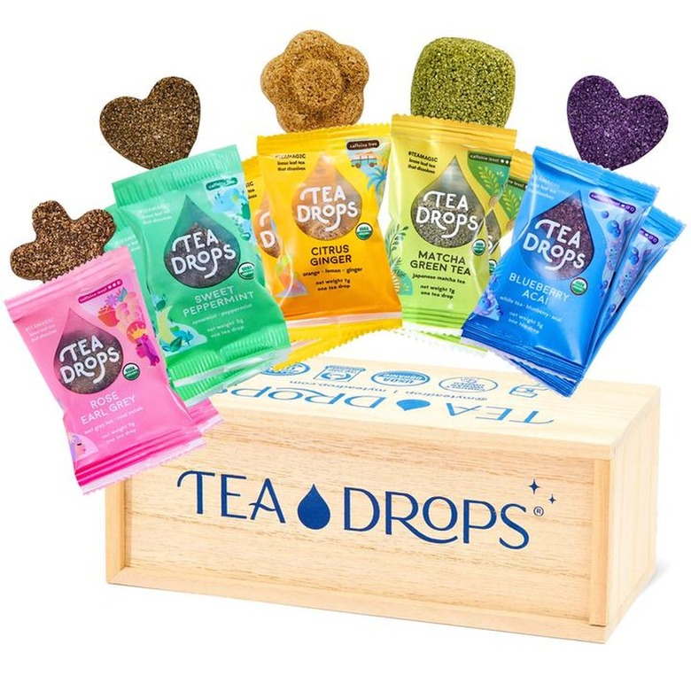 five packets of tea with different shapes and a wood box that reads tea drops