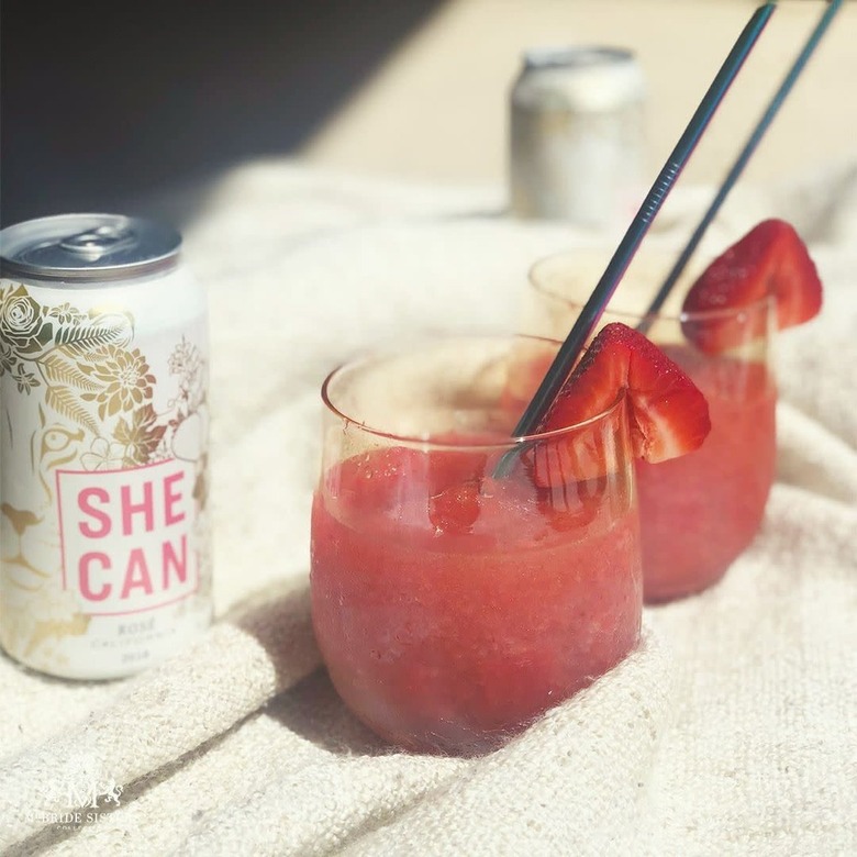 can that reads she can next to two glasses with red liquid and black straws