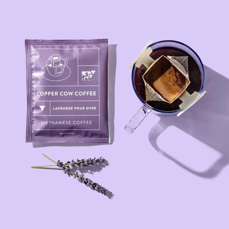 purple package that reads copper cow coffee near lavender and coffee filter on mug