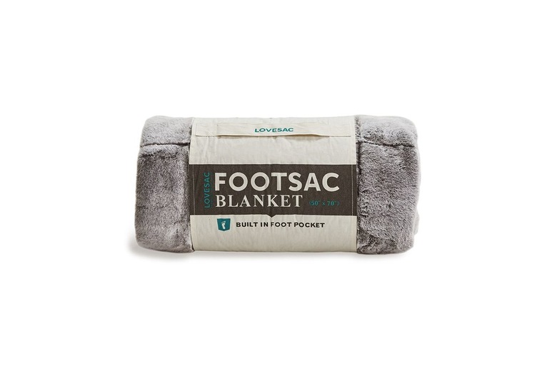 A FootSac blanket wrapped up in it's packaging: a small piece of burlap is wrapped around the blanket with text that reads LoveSac FootSac blanket. Built in Foot Pocket