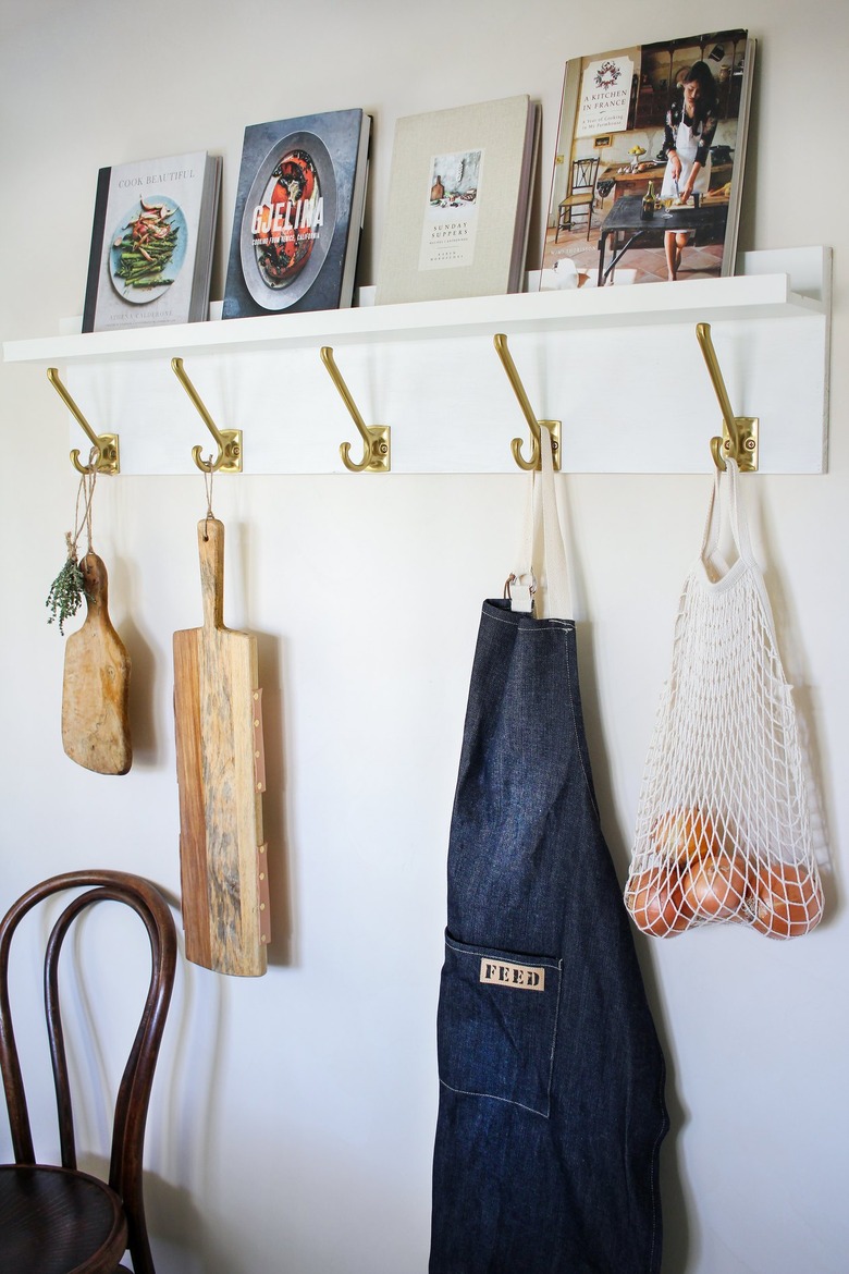 White kitchen wall hangers with gold hooks holding cutting boards