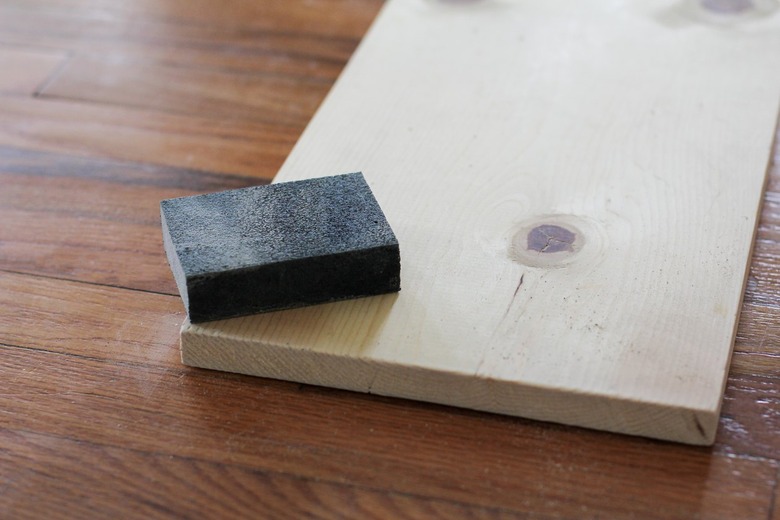 Sanding block resting on flat piece of plywood on wood flooring