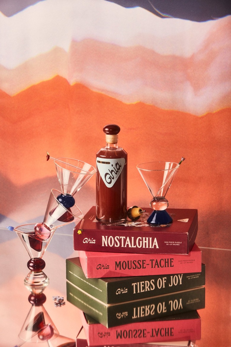 A bottle of Ghia on a pile of books with martini glasses staged around
