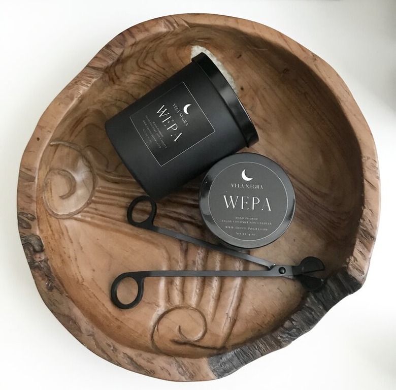 black candles and wick trimmer in wood bowl
