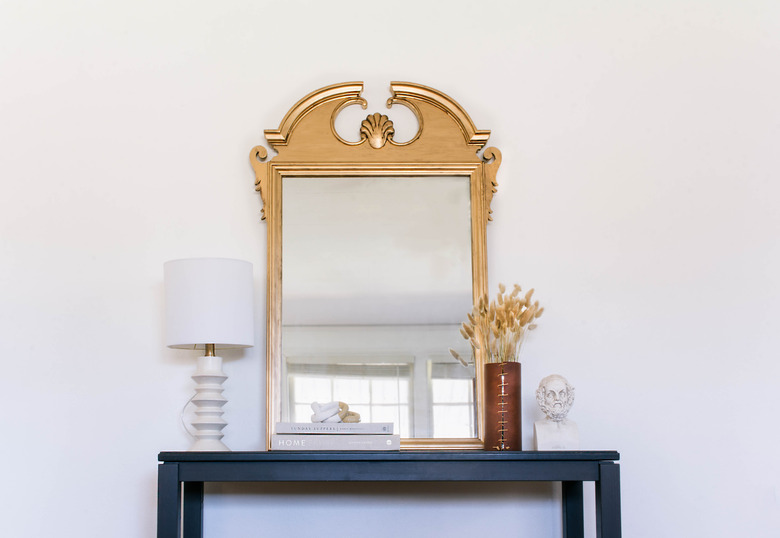 DIY antique gilt mirror hanging on wall above black table with lamp