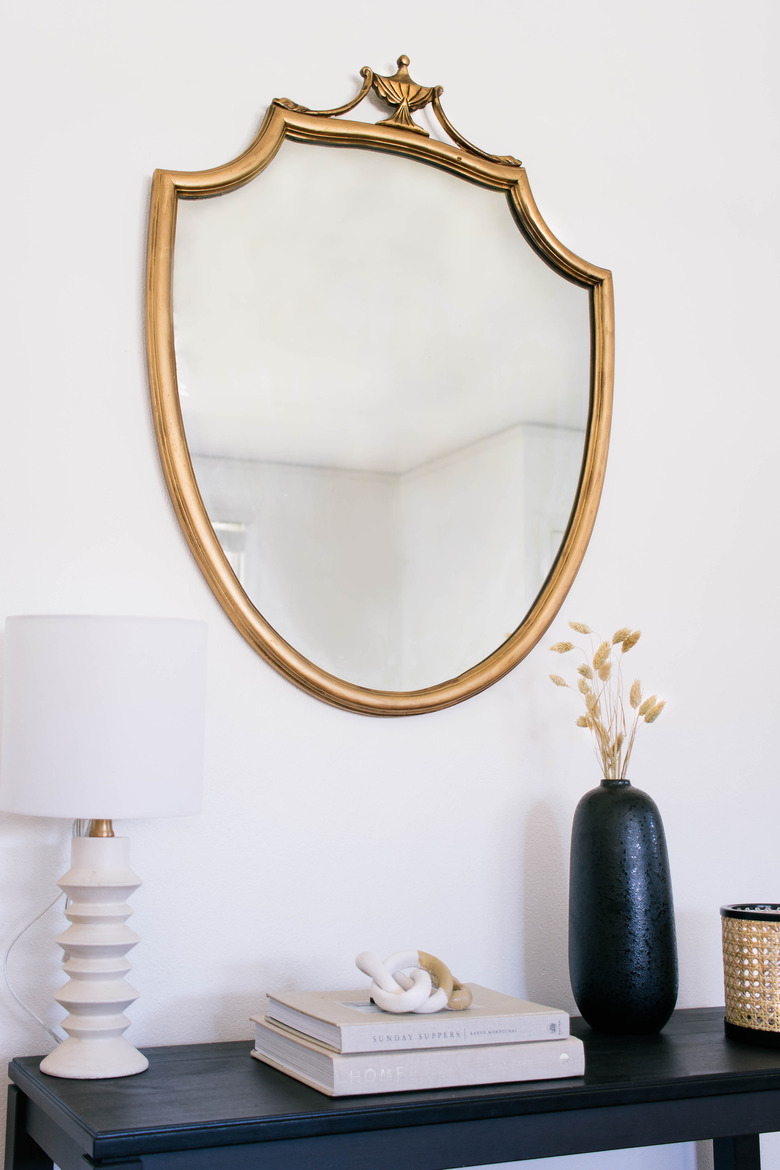 DIY antique gilt mirror hanging on wall above black table with lamp