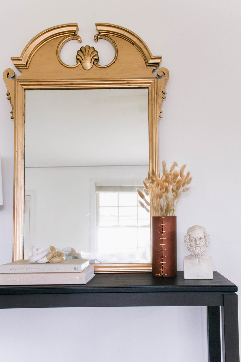 DIY antique gilt mirror leaned against wall on black table with books