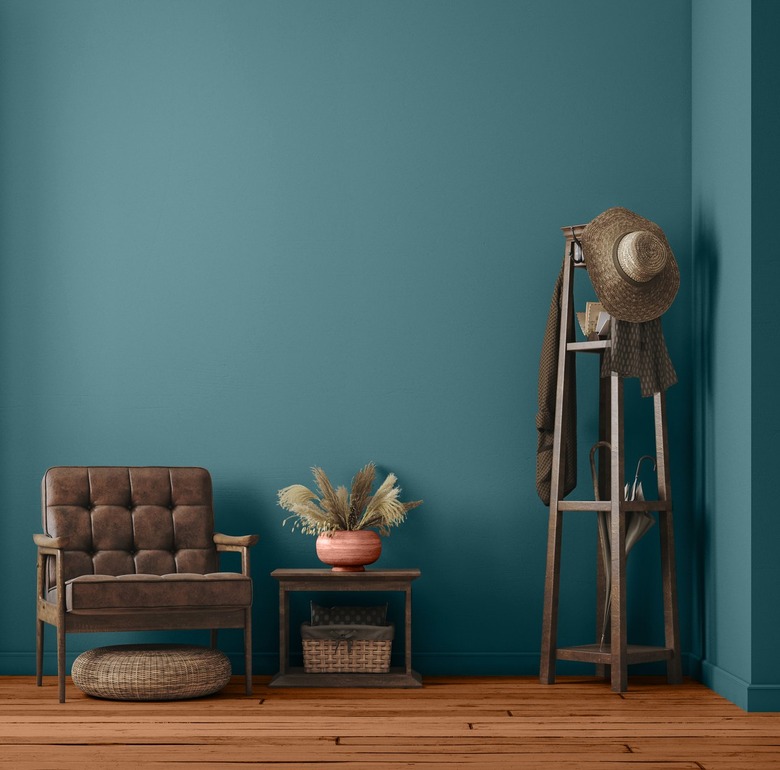 The teal Vining Ivy paint on a wall behind a brown armchair