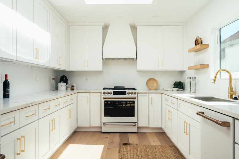 White kitchen cabinets with brass hardware and plumbing fixtures
