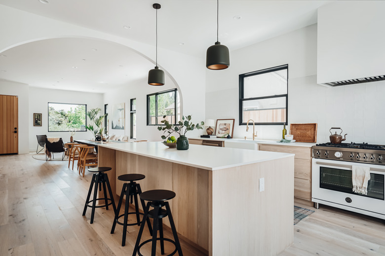 Open white and wood kitchen with large kitchen island and black pendants