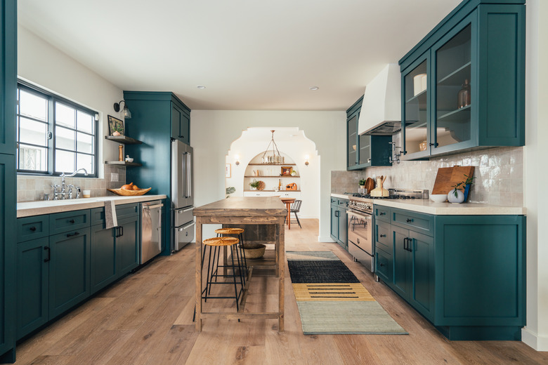 Kitchen painted with green cabinets with a wood kitchen island table