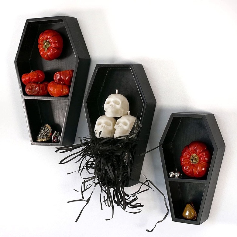 three black coffin-shaped shelves with vegetables and kitchen tools