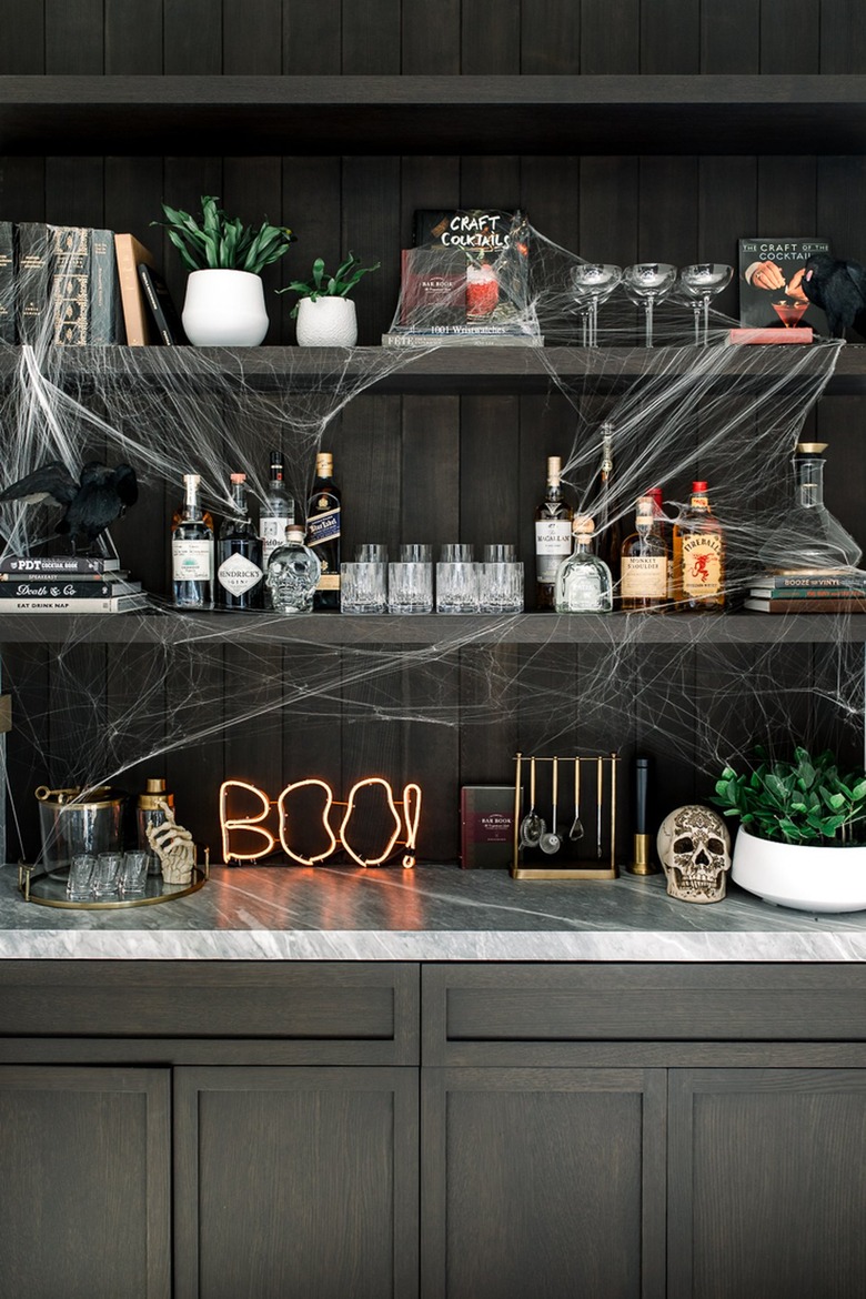 Bookshelf with drink supplies and a spiderweb decaling.