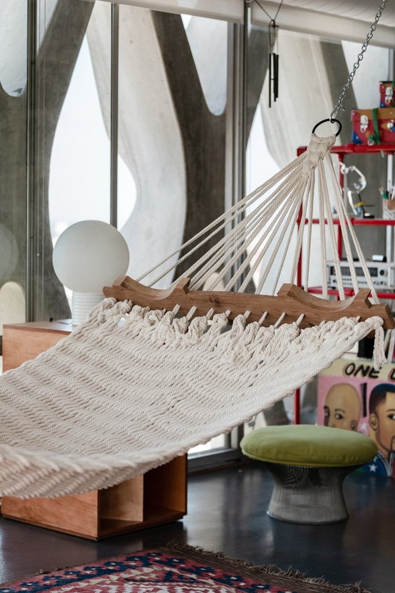 Hammock hanging in front of tall loft windows.