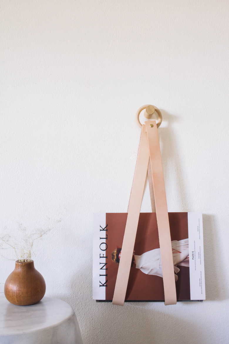 diy leather & wood magazine holder hanging on wall with kinfolk magazine inside
