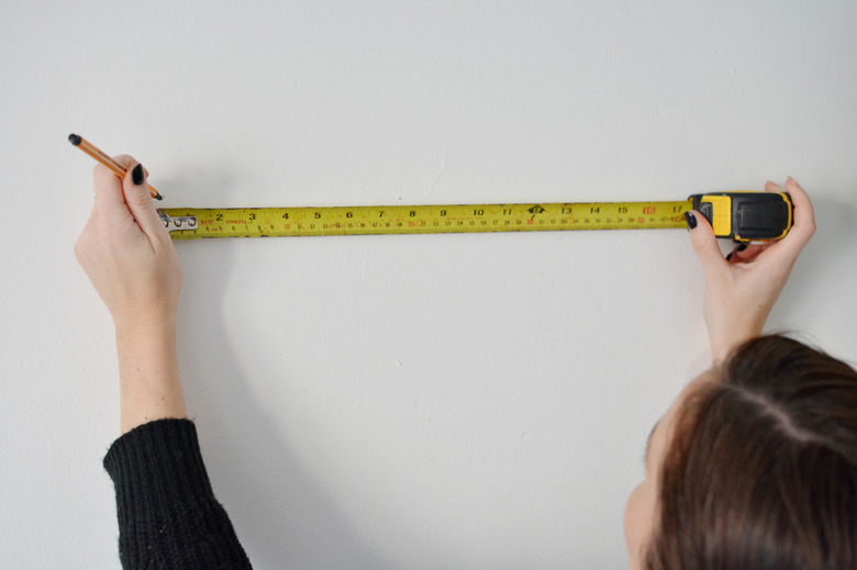Person holding an extended tape measure againist a white wall