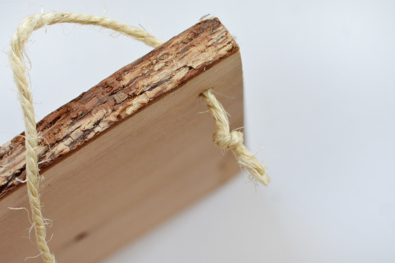 Piece of wood with a grain edge with some rope threaded through with a knot at the end