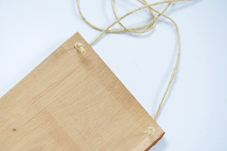 Piece of wood with some natural coloured rope threaded through the corners.