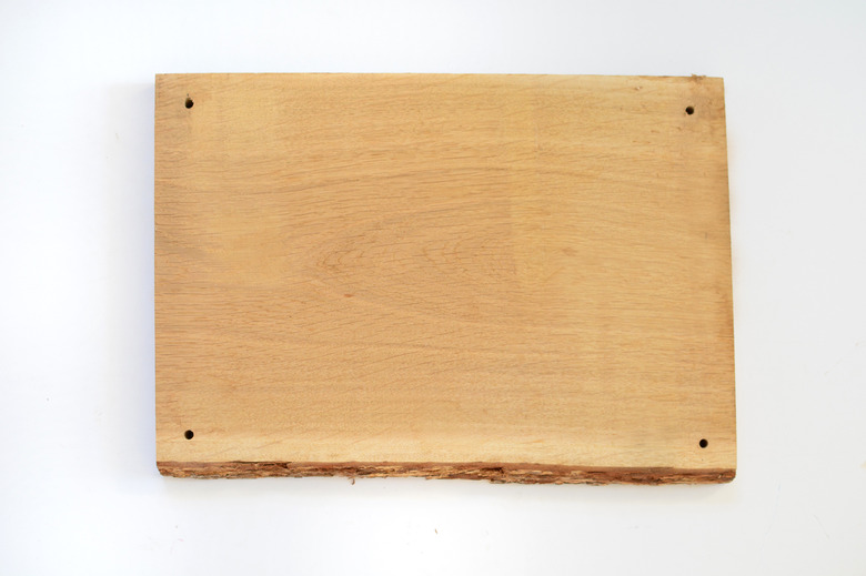 Piece of natural hardwood with a hole drilled through each corner