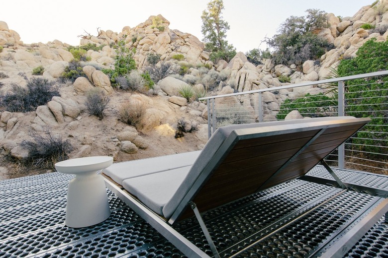 a chaise lounge on a patio with a metal floor and railing