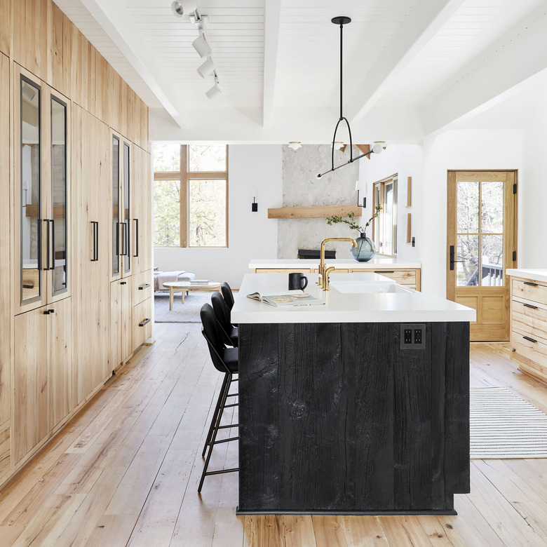 hardwood kitchen flooring in rustic space with wood cabinets and black island with white countertops