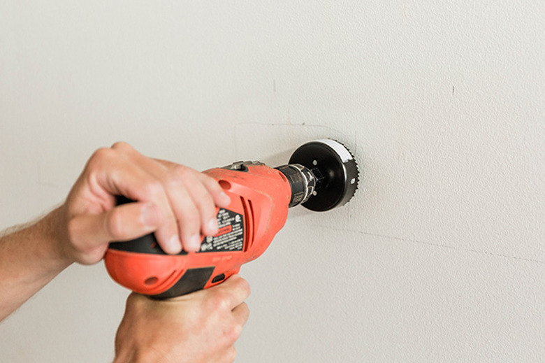 Drill a hole behind where the TV sits on the wall.