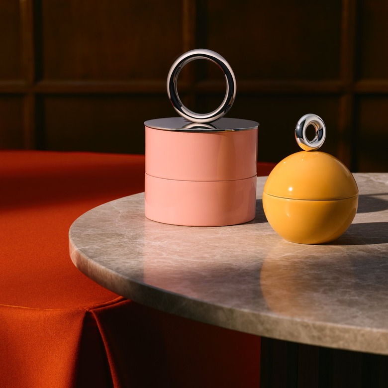 Two uncommon matters and H&M Home trinket boxes rest on a marble table. One is pink with a silver ring on the top