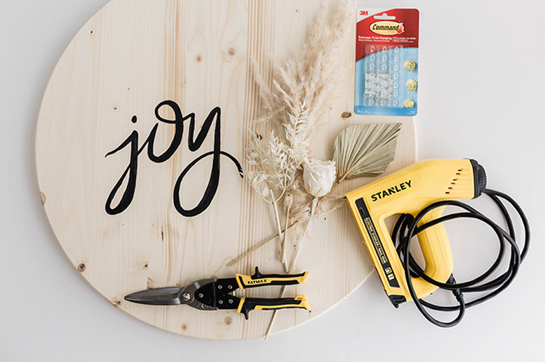 Attach the dried flowers to your wooden circle using temporary Command hooks or more permanent staples.