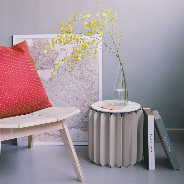 Circular folded paper table with vase on top and books leaning against it