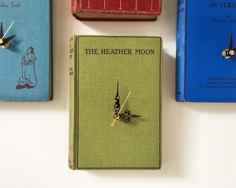 Four wall clocks with book-cover faces in different colors