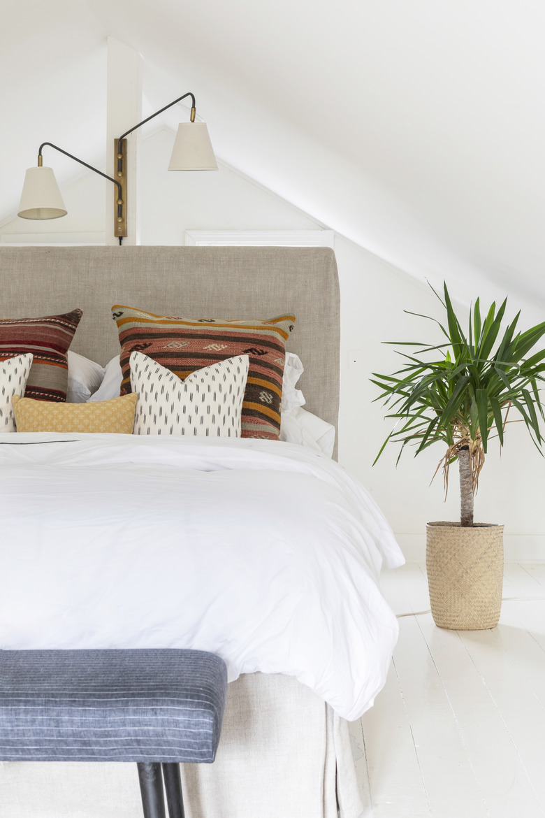 Boho pillows on bed with cream fabric headboard