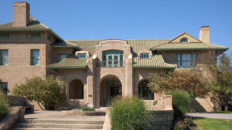 a beige modern Spanish style house with a green roof.