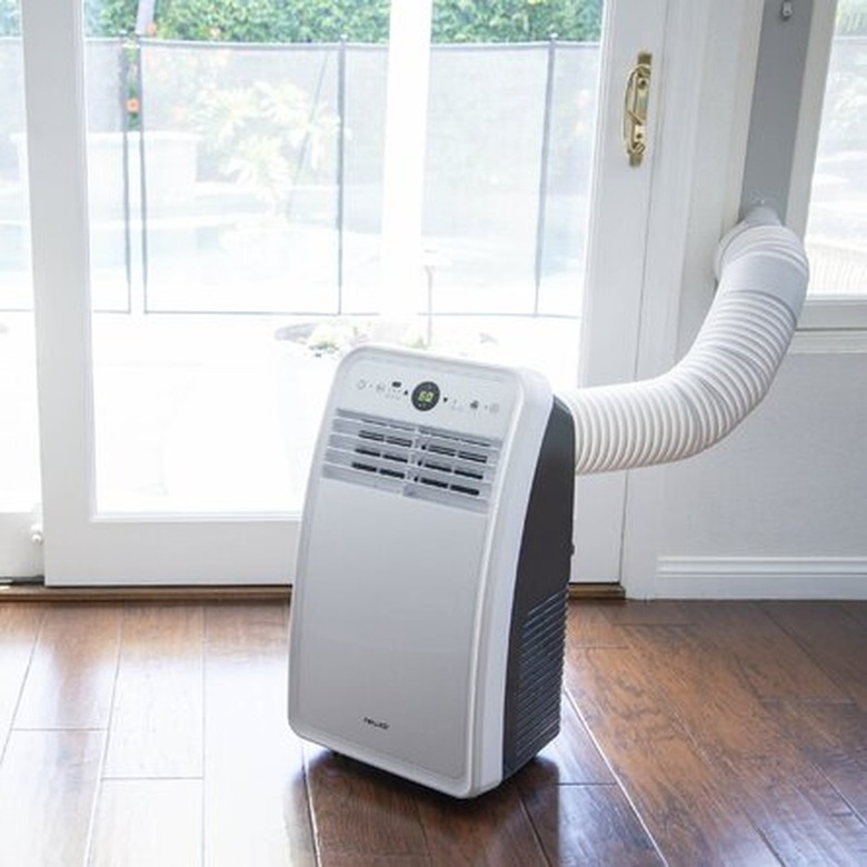 A portable AC in a living area with wood floors and a glass door