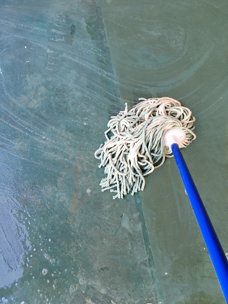 A white yarn mop on a concrete floor.