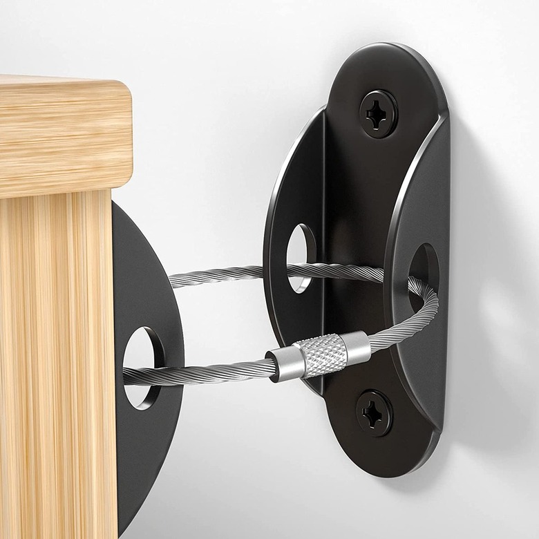 A metal furniture anchor with a steel wire attached to a piece of furniture