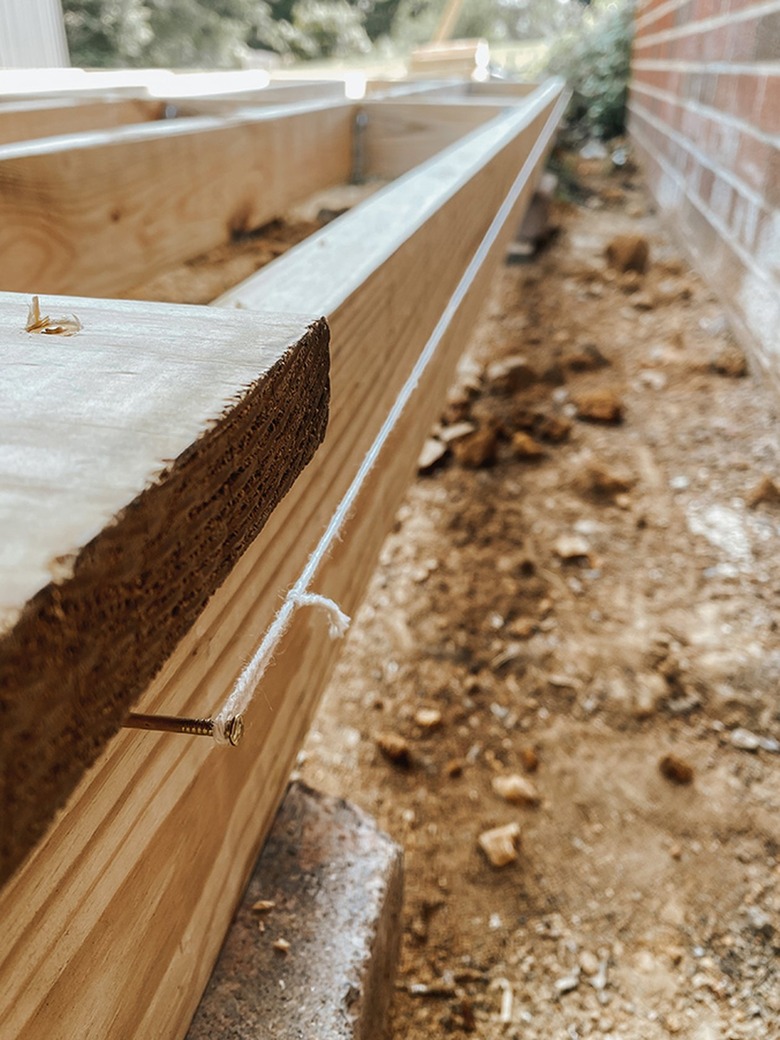 Nail a temporary string guide to the back side of the deck frame.