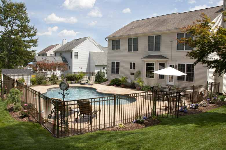 Lush backyard pool and patio behind colonial style home.