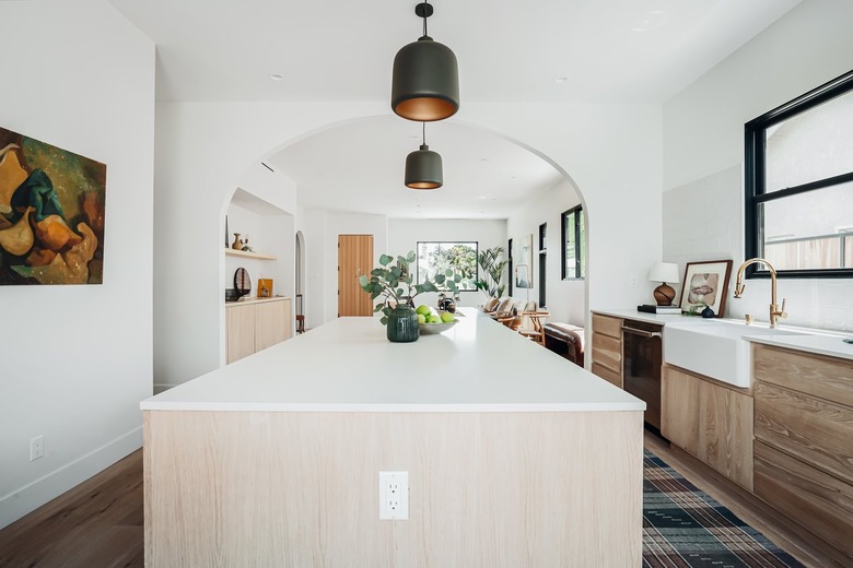 Large white and wood kitchen island with black pendant lights