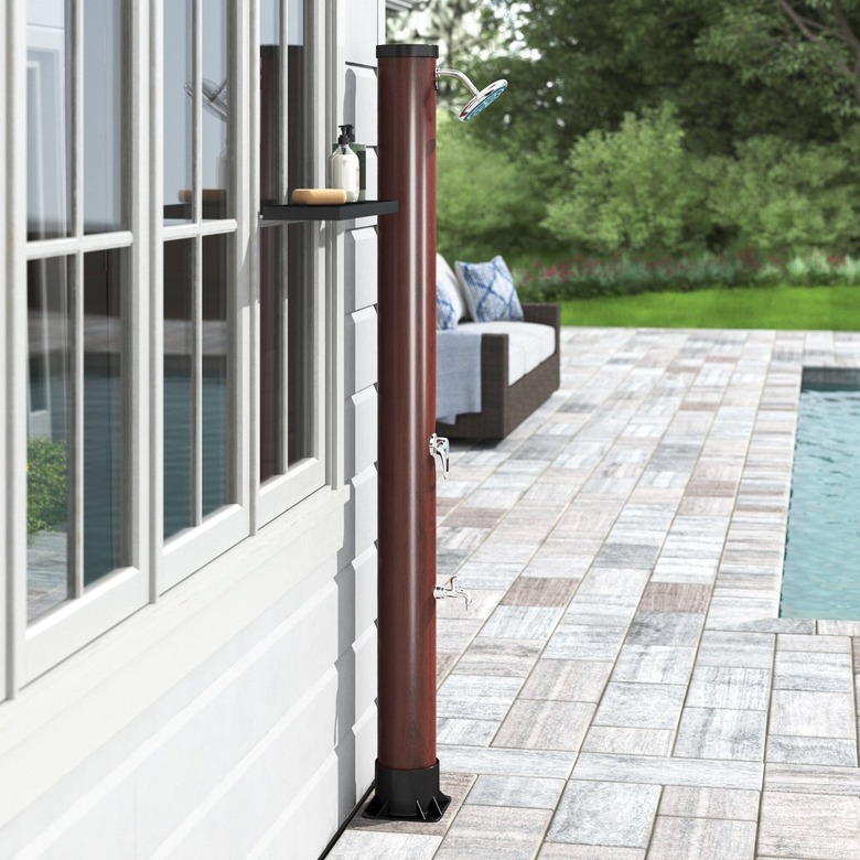 A freestanding outdoor shower by a backyard pool