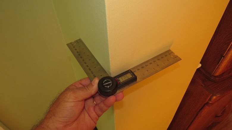 Digital protractor being used on an outside wall corner.