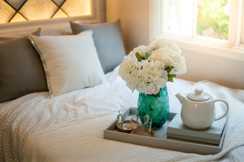 Bedroom decorative objects on the bed in cozy vintage bedroom. Flower vase